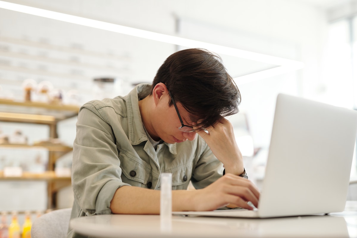 Egy férfi a laptop előtt ül, és koncentrációs zavarokkal küzd. A csendes migrén tünetei, kockázati tényezői és enyhítése