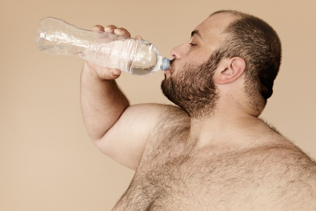 Túlsúlyos férfi vizet iszik. Fókuszban a vesekő - Okai, kezelése és megelőzése