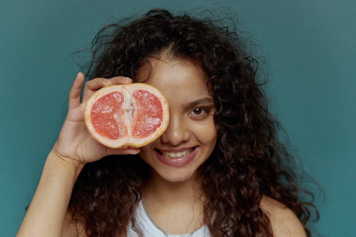 Félbevágott grapefruitot maga elé tartó nő. A grapefruitmag-kivonat egészségügyi előnyei