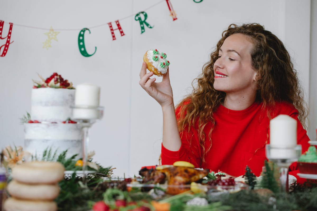 Karácsonyi süteményeket fogyasztó nő. 15 gyógynövény a puffadás enyhítésére az ünnepek alatt